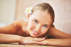 Portrait of young female with grangipani flower in hair looking at camera