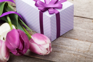 Fresh tulips bouquet and gift box on wooden table with copy space